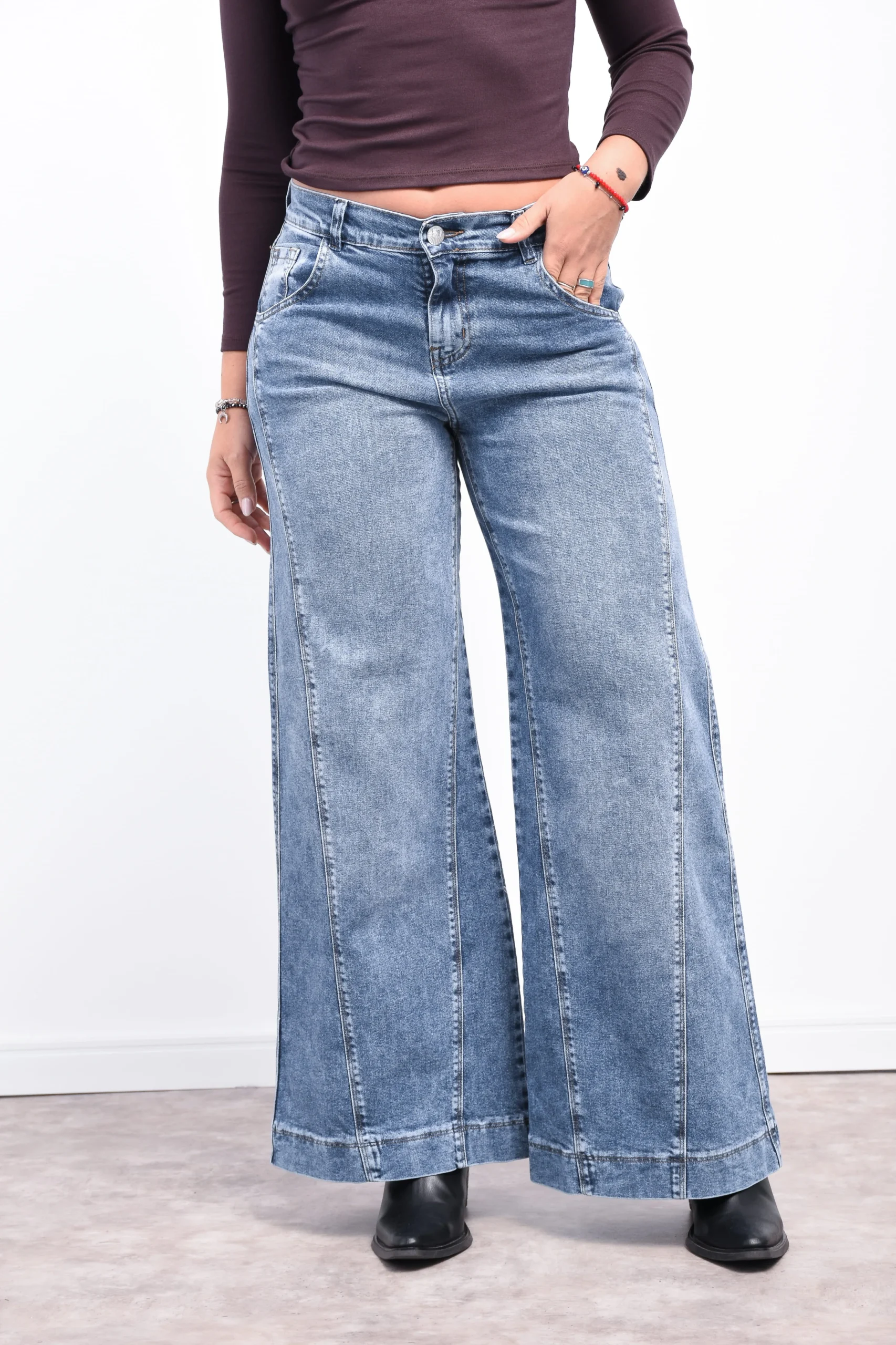 Detalle frontal del jean maxi wide leg renata elastizado, con las manos en los bolsillos mostrando el tiro alto