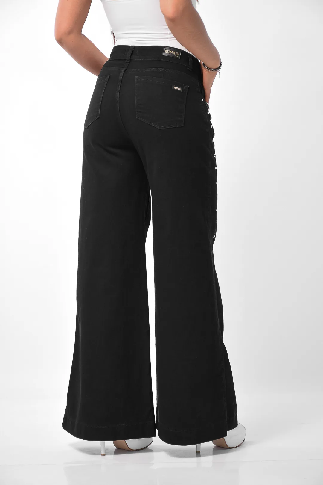 Silueta lateral de pantalón denim negro con tachas metálicas laterales