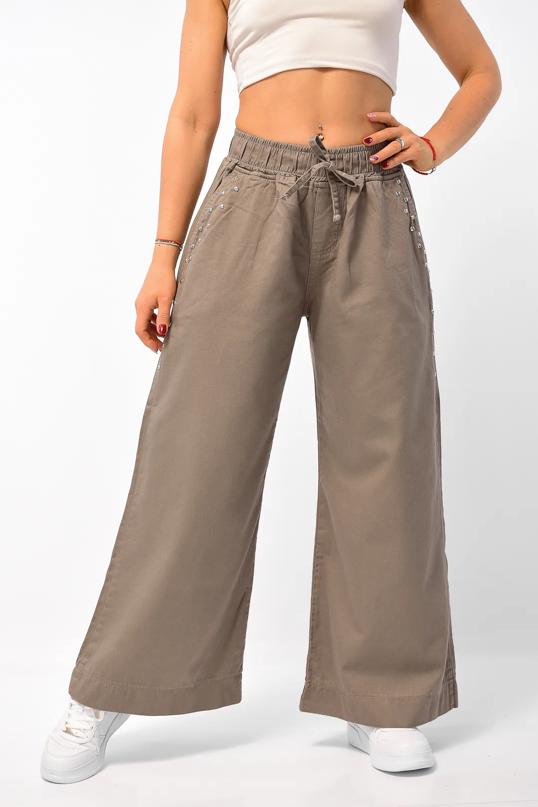 Detalle de bolsillo frontal con tachas metálicas plateadas en pantalón maxi wide leg visón de gabardina rígida Art. Rocío.